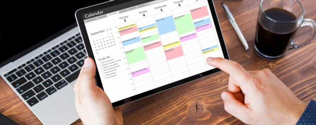 Mann benutzt Kalender-App auf Tablet bei der Arbeit